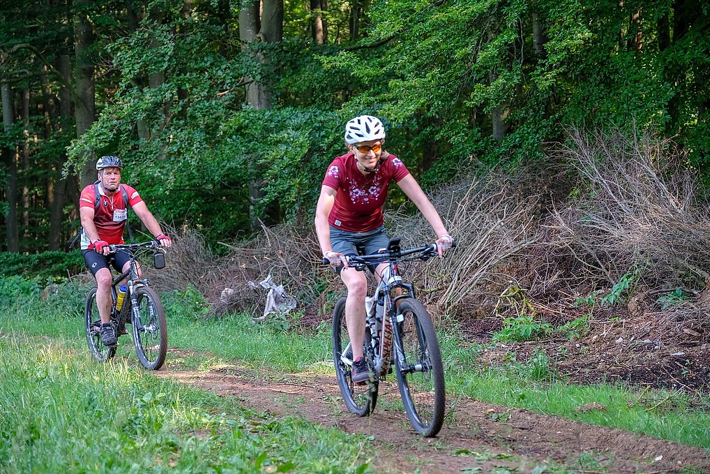 Bild von zwei Menschen die hintereinander auf Moutainbikes fahren
